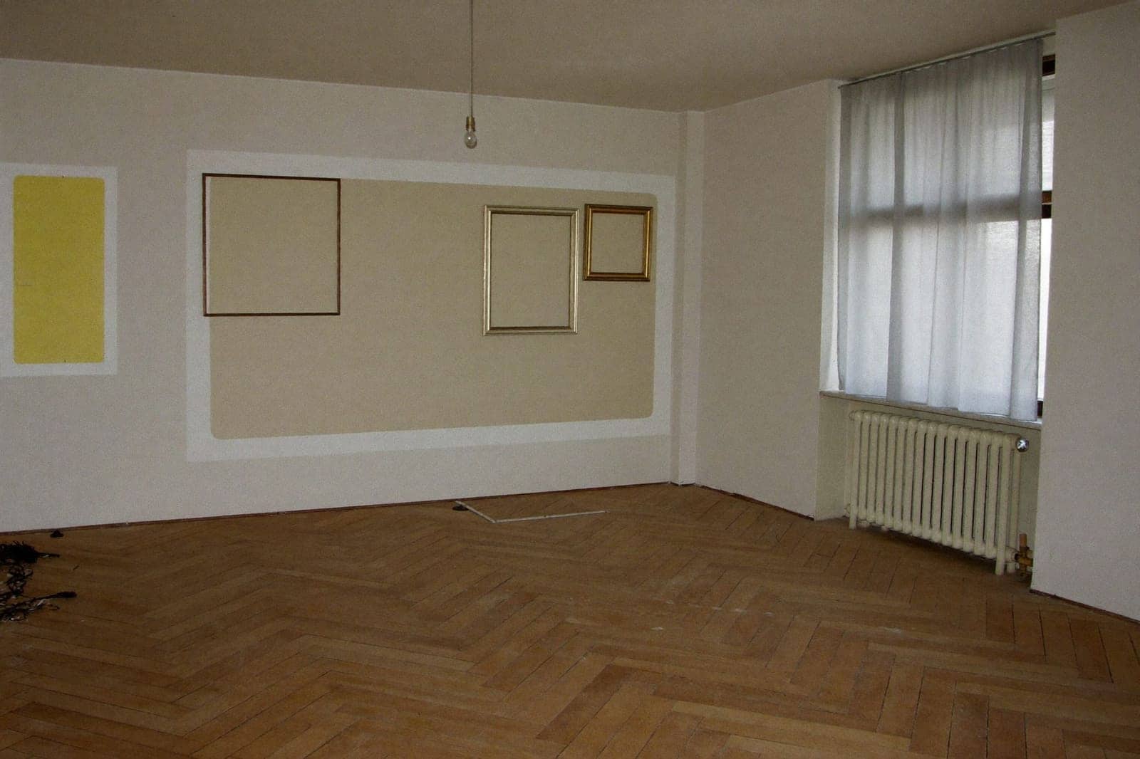 Volledig leeggemaakte woonkamer met bezemschone parketvloer na het leegmaken van een woning