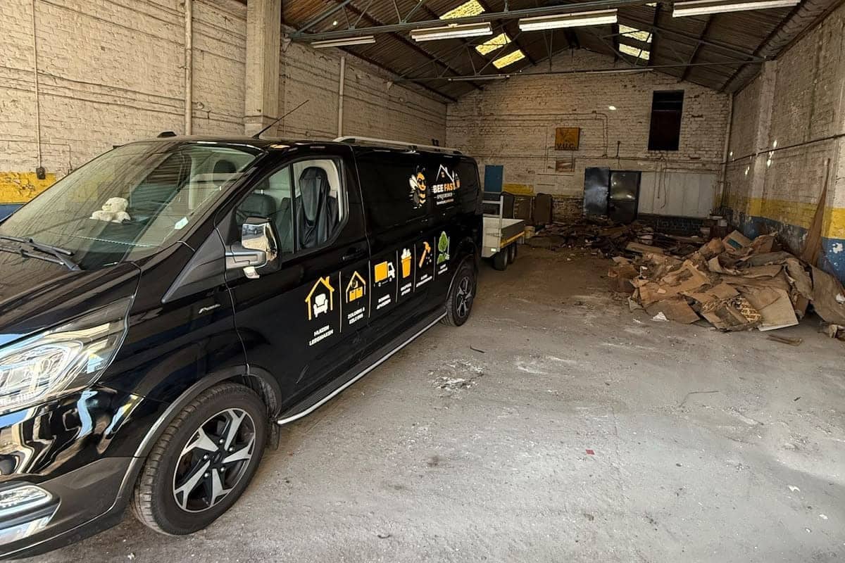De bestelwagen van Bee Fast in een loods die wordt leeggehaald, met het laatste afval nog achteraan