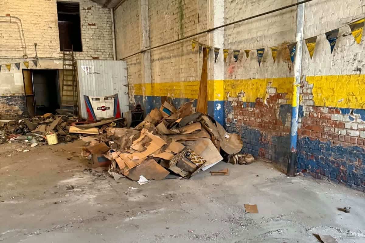 Hoop hout, karton en bouwafval tegen de muur van een loods voor de opruiming